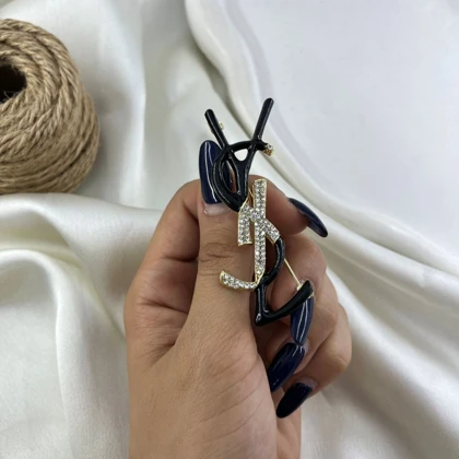 گل سینه زنانه طرح لوگو مدل آیکون مشکی طلایی نگین‌دار