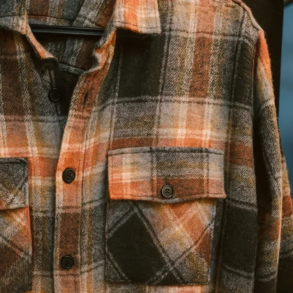 پیراهن پشمی چهارخونه با پارچه برس‌خورده نرم با ترکیب رنگ نارنجی سوخته، مشکی و بژ با ته‌مایه‌های قهوه‌ای خاکی