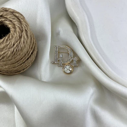 گل سینه زنانه مدل درخشان طرح Dior نگین‌دار طلایی